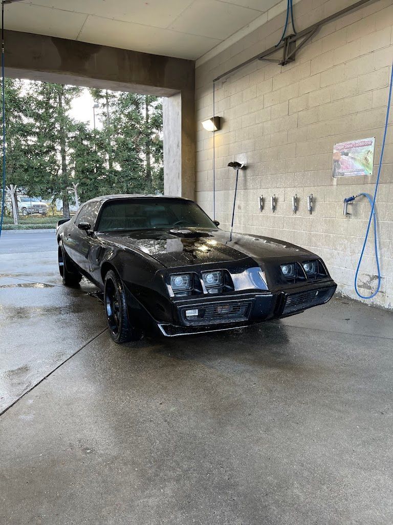 Black Trans Am in a car wash bay.