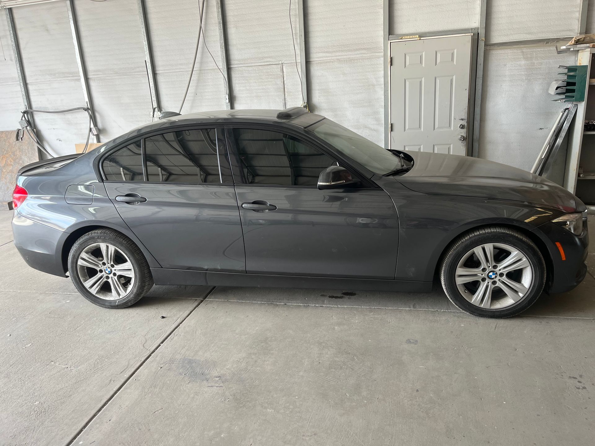 A car is being repaired in a garage with the hood open.