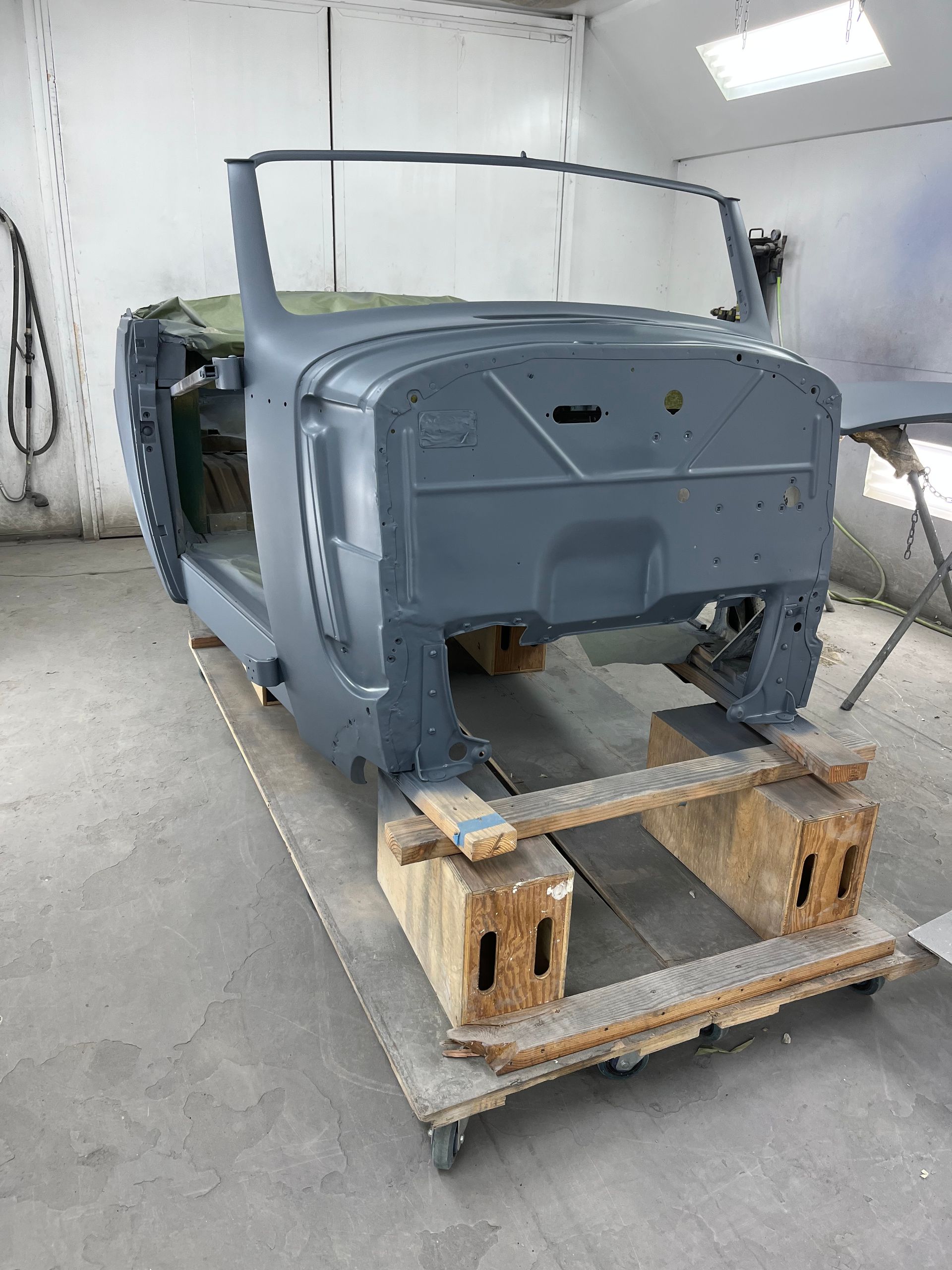 Gray car frame on a wooden support in a workshop, ready for restoration.