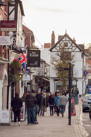 A group of people are walking down a street with a sign that says the lamb