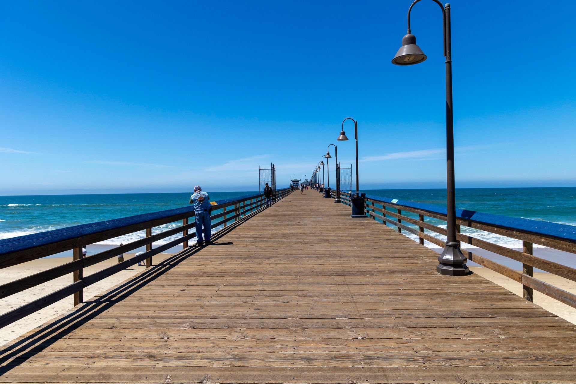 a man stands on a pier looking at the ocean