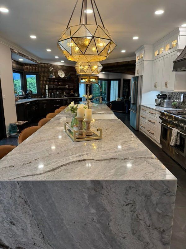 A kitchen with a large island and marble counter tops.
