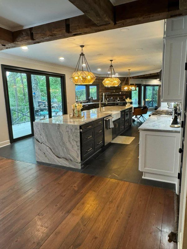 A kitchen with white cabinets , a stove , a sink , and a window.