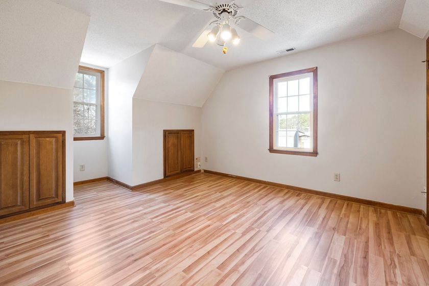 An empty room with hardwood floors and a ceiling fan.
