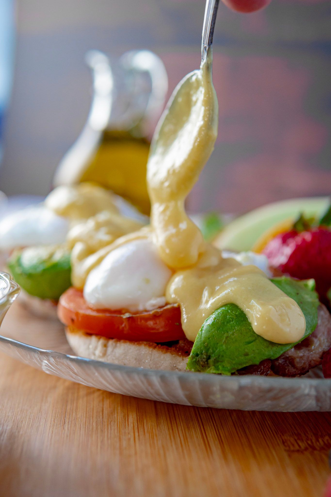 A close up of a person pouring sauce on a sandwich on a plate.