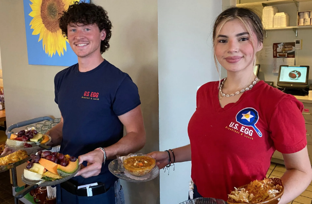 A man and a woman are standing next to each other holding plates of food.