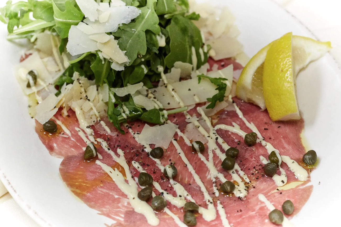 A close up of a plate of food with meat and vegetables on a table.