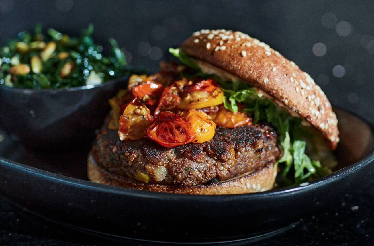 A close up of a hamburger on a bun on a plate.