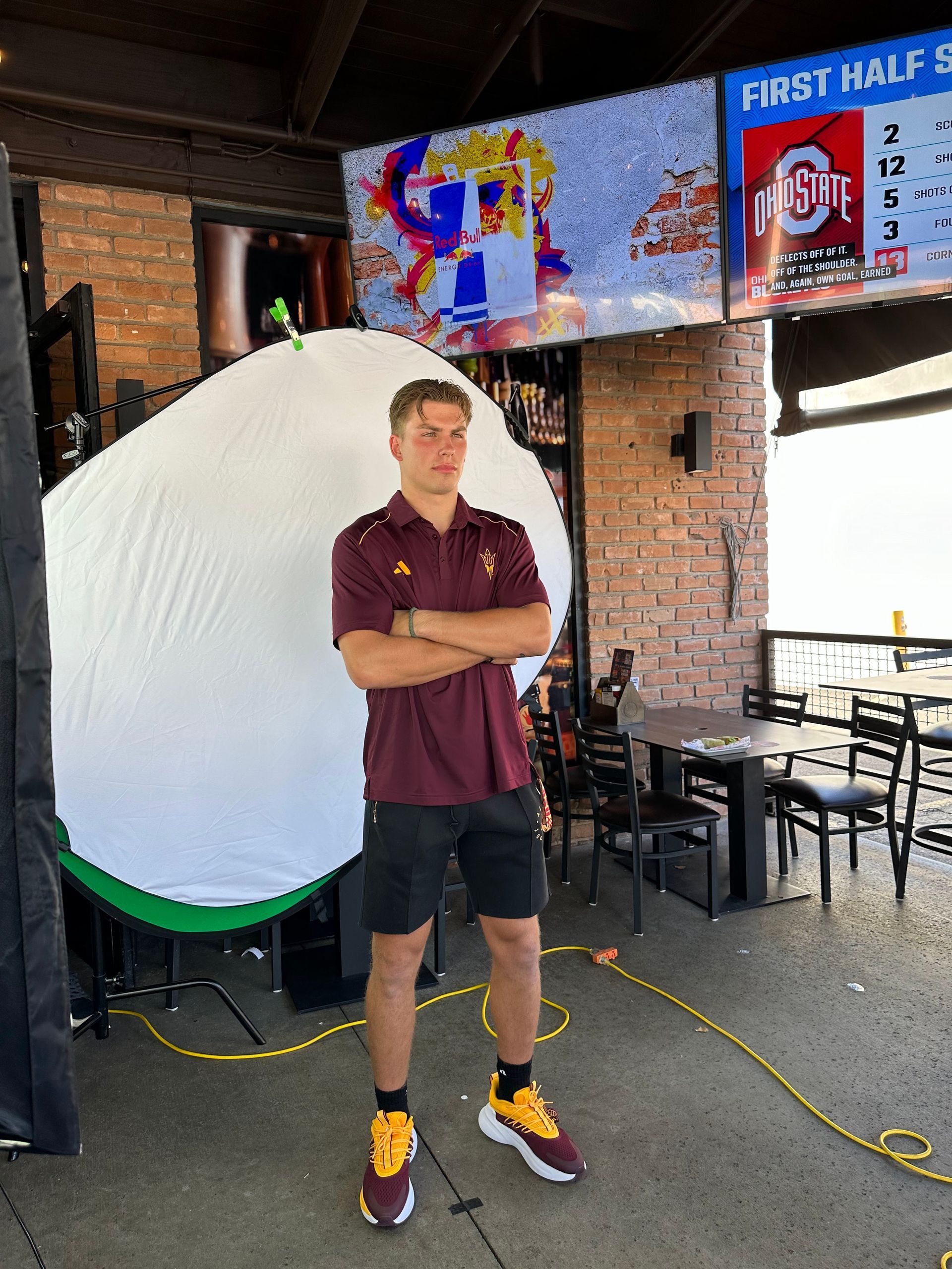 A man in a maroon shirt is standing in front of a large white object.