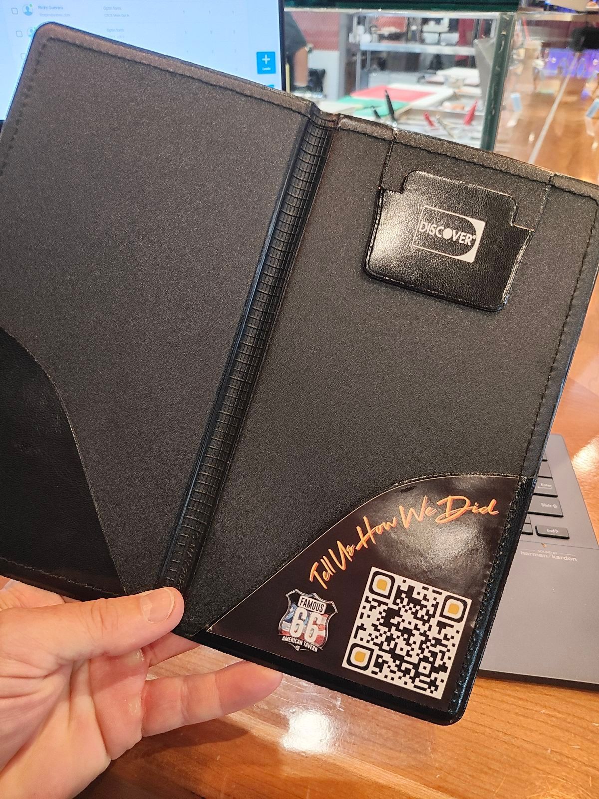 A person is holding a black wallet with a qr code on it
