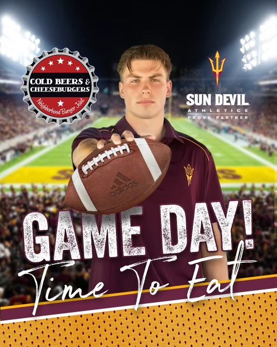 A man is holding a football in front of a football field.