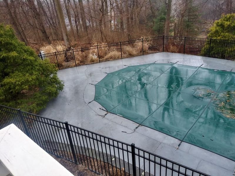 A swimming pool with a green cover and a black fence