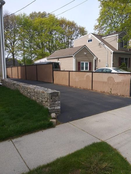 A driveway with a fence and a house in the background