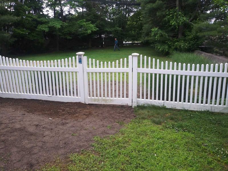 A white picket fence surrounds a lush green yard