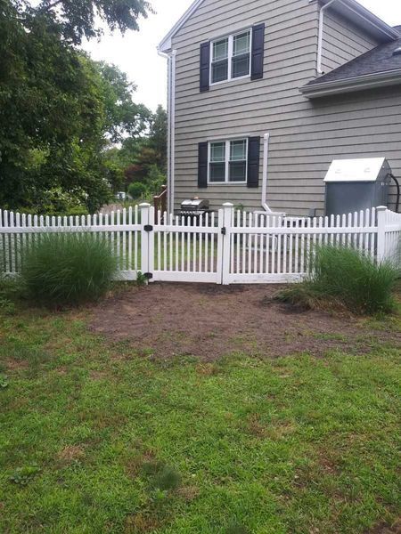 A white picket fence is in front of a house.