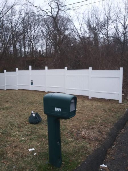 A white fence with a green mailbox in front of it