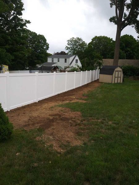 A white fence surrounds a lush green yard