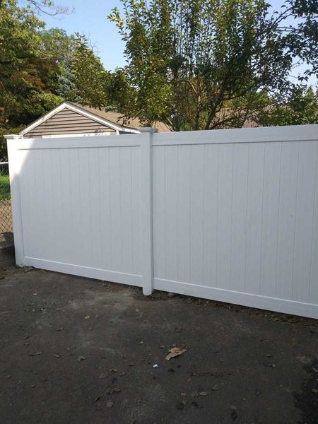 A white vinyl fence is sitting in front of a house.