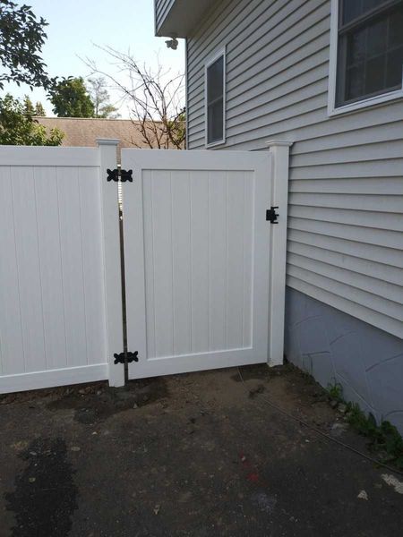 A white fence with a gate in front of a house