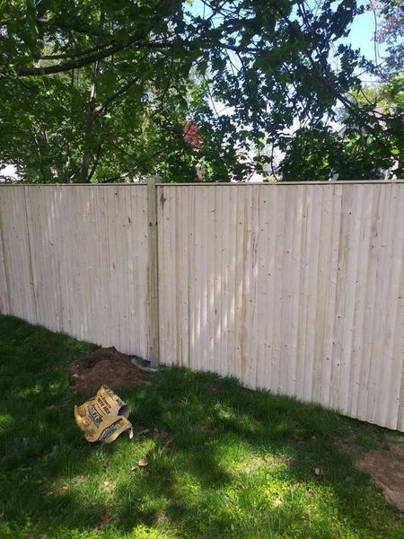 A white wooden fence is sitting on top of a lush green lawn.