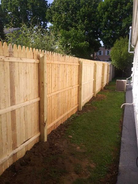 A wooden fence is in the backyard of a house.