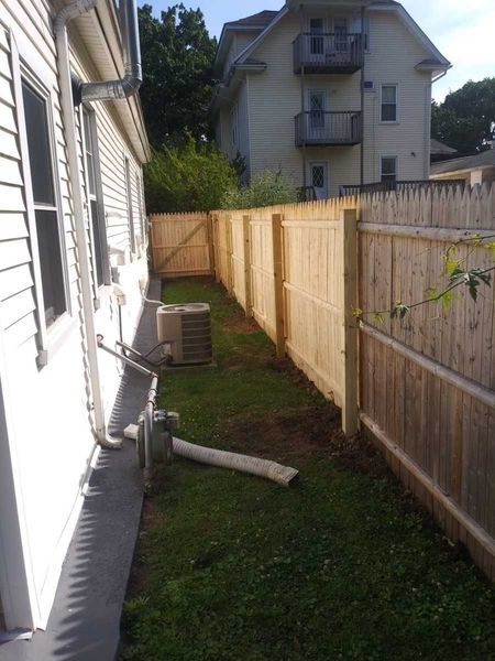 A wooden fence is in the backyard of a house