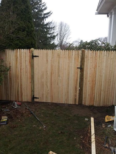 A wooden fence with a gate in the backyard of a house.