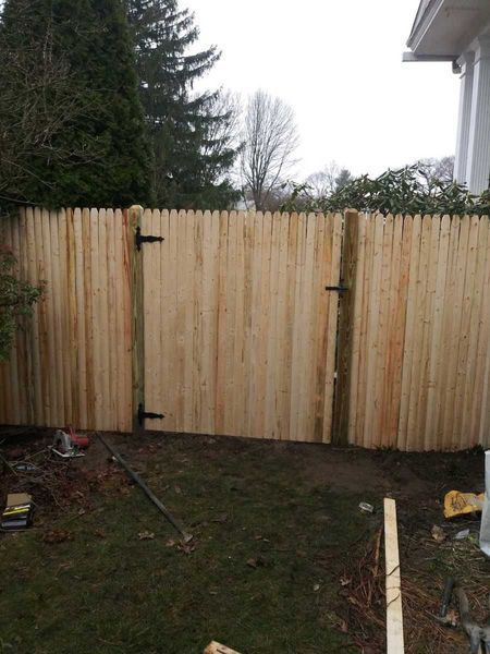 A wooden fence with a gate in the backyard of a house.