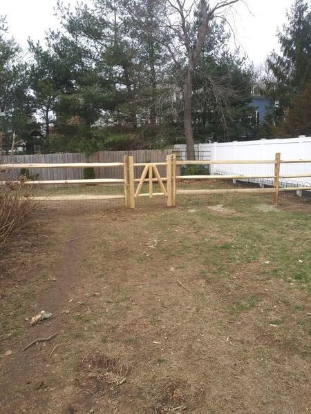 A wooden fence with a gate in the middle of a field.