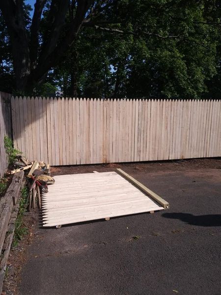A wooden fence is sitting in the middle of a parking lot.