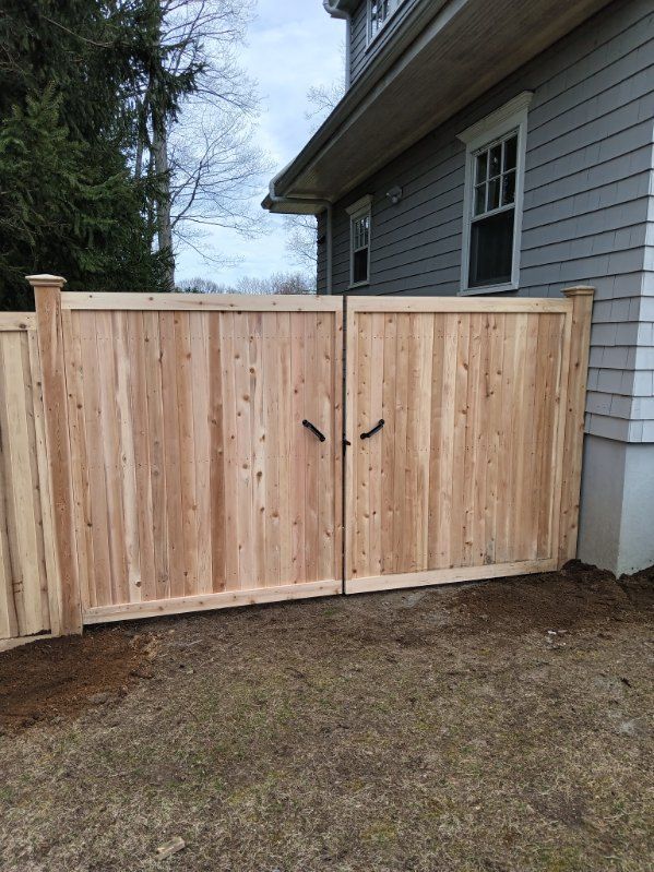 A lush green lawn with a wooden fence and houses in the background