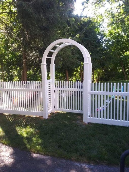 A person is painting a wooden fence with a brush.