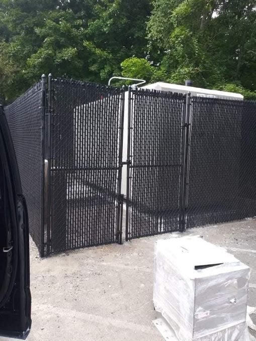 A man is using a drill to install a chain link fence.