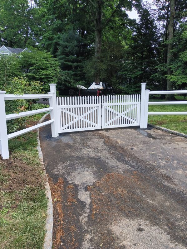 A wooden fence surrounds a playground in a parking lot