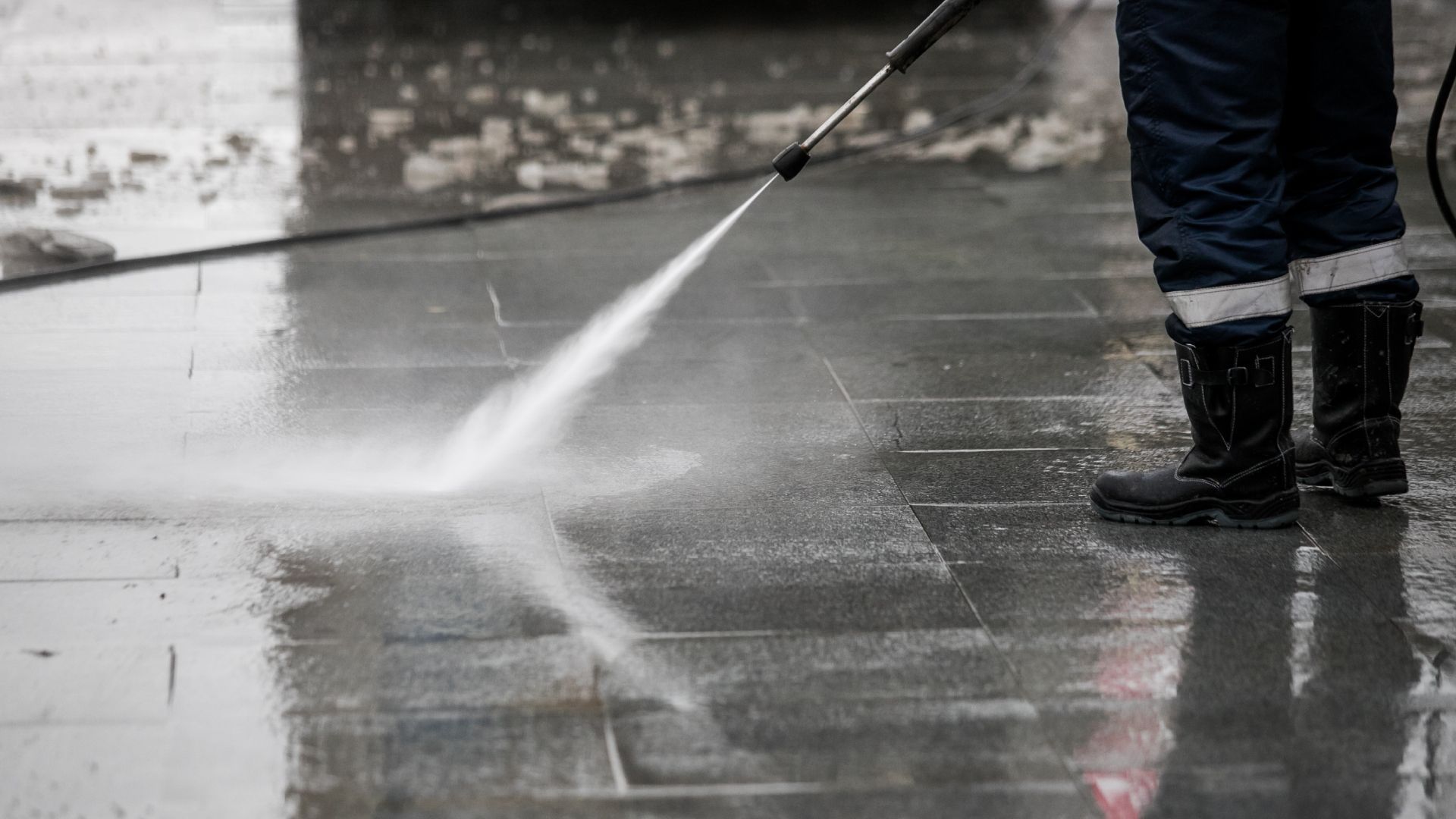 A man is using a drill to install a chain link fence.