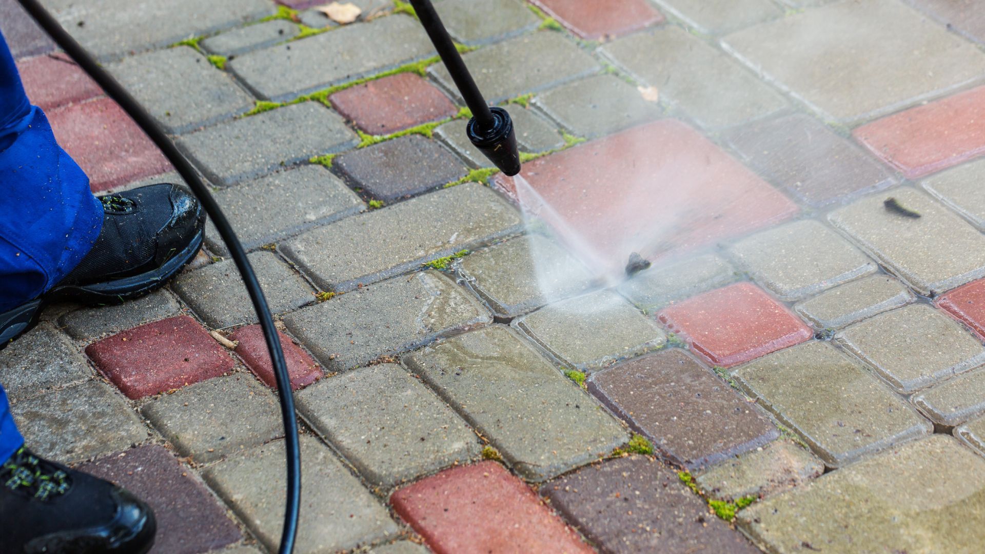 A man is using a drill to install a chain link fence.
