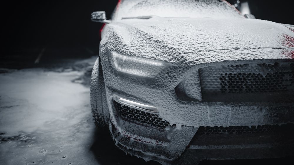 A black and white photo of a car covered in foam.