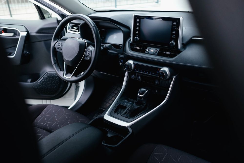 The interior of a car with a steering wheel and a radio.