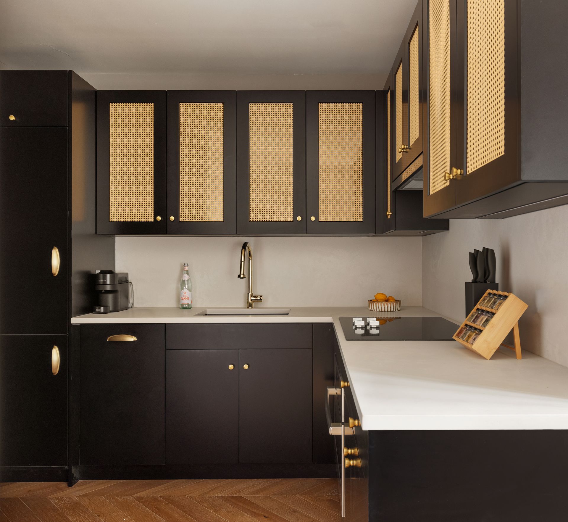 Black kitchen with gold accents and white countertops.