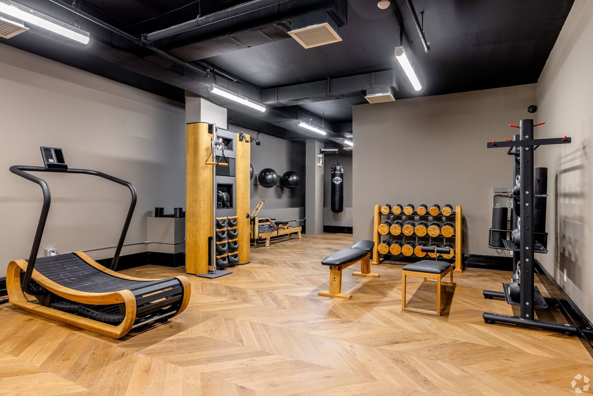 Gym with wooden floors and various workout equipment like a treadmill and weights.