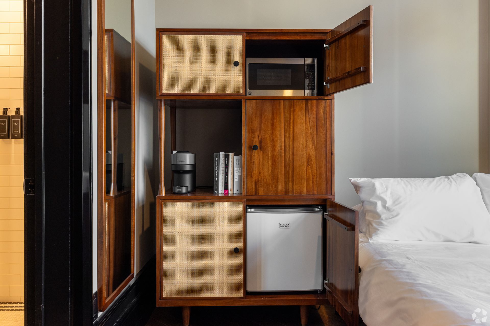 Wooden cabinet with a microwave, mini fridge, and coffee maker in a hotel room.