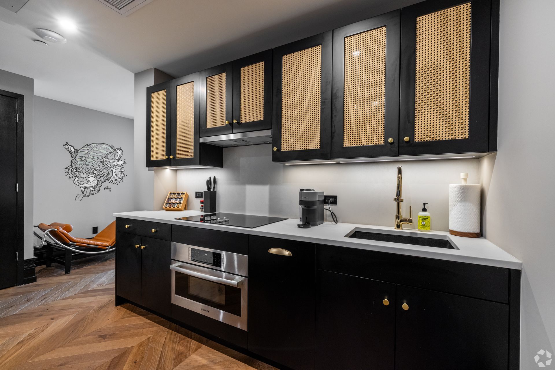 Modern kitchen with black cabinets, gold accents, and stainless steel appliances.