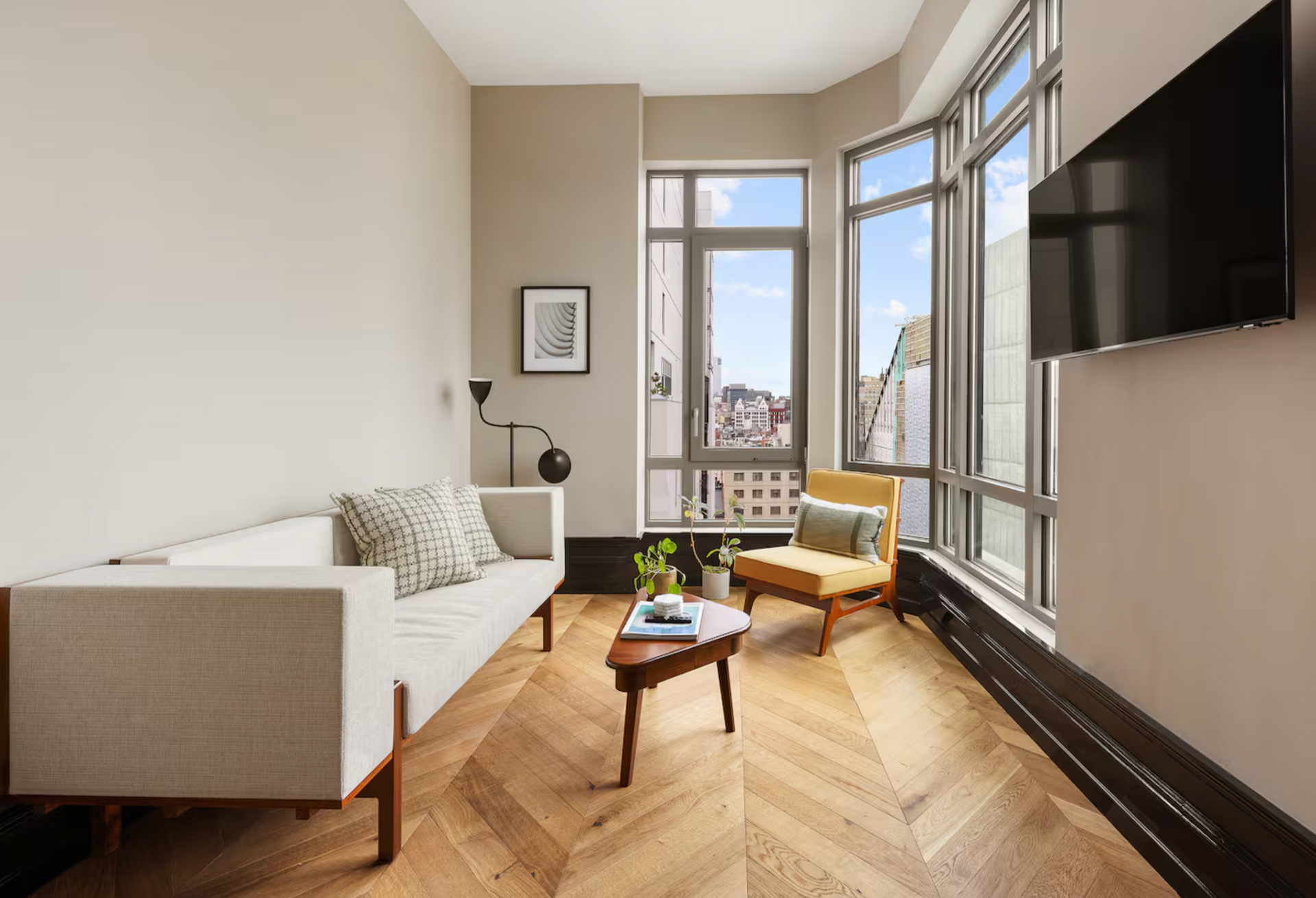 Living room with white sofa, yellow chair, wooden floor, and large windows.