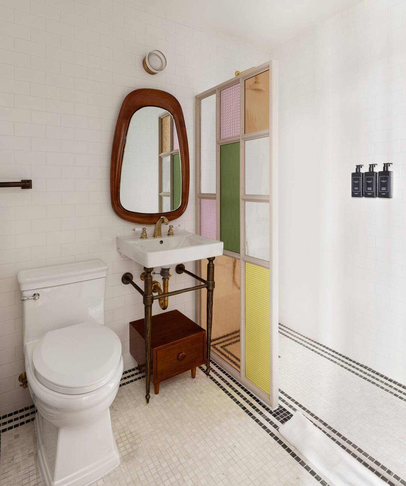 Bathroom with white tile, a vintage-style vanity, a colorful glass shower door, and a toilet.