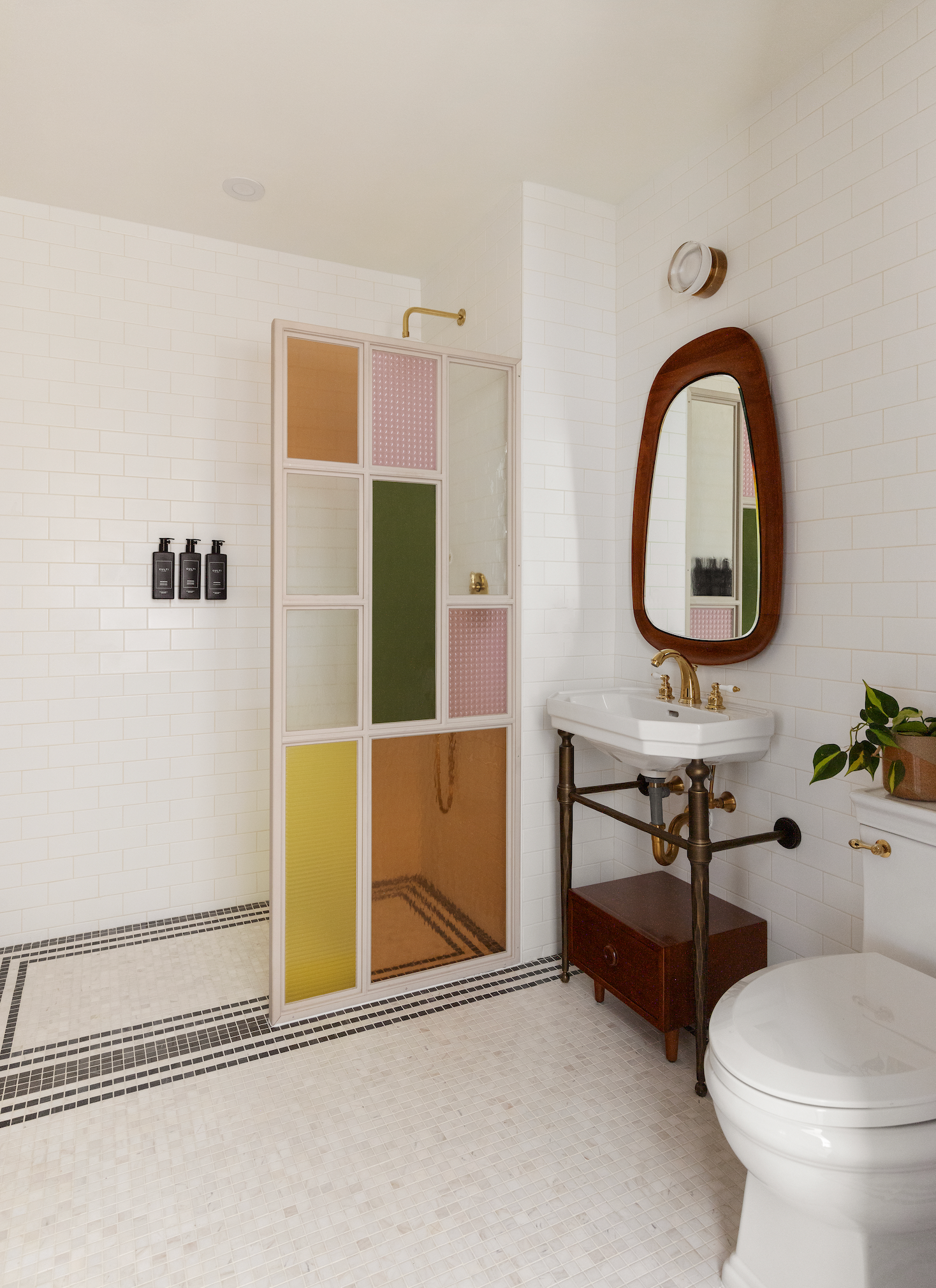 Bathroom with colorful glass shower screen, marble sink, and white tile walls.