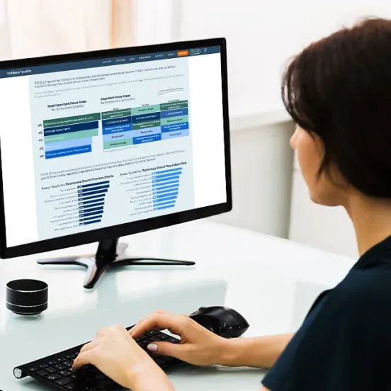 A woman is typing on a keyboard in front of a computer monitor