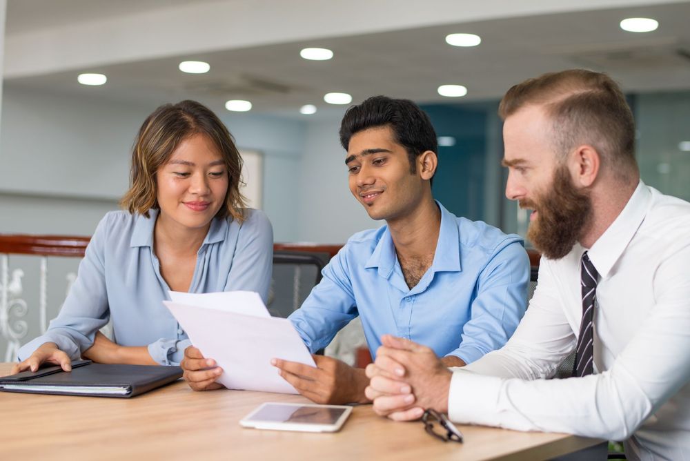 A group of people are sitting at a table looking at a piece of paper.