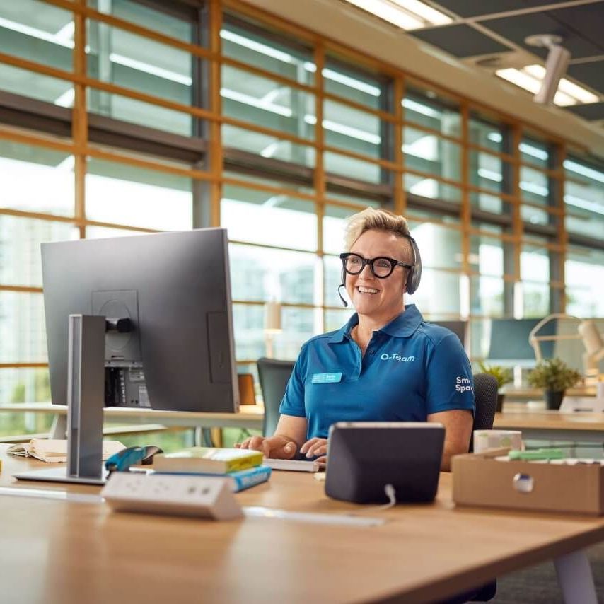 A woman wearing headphones is sitting at a desk in front of a computer.