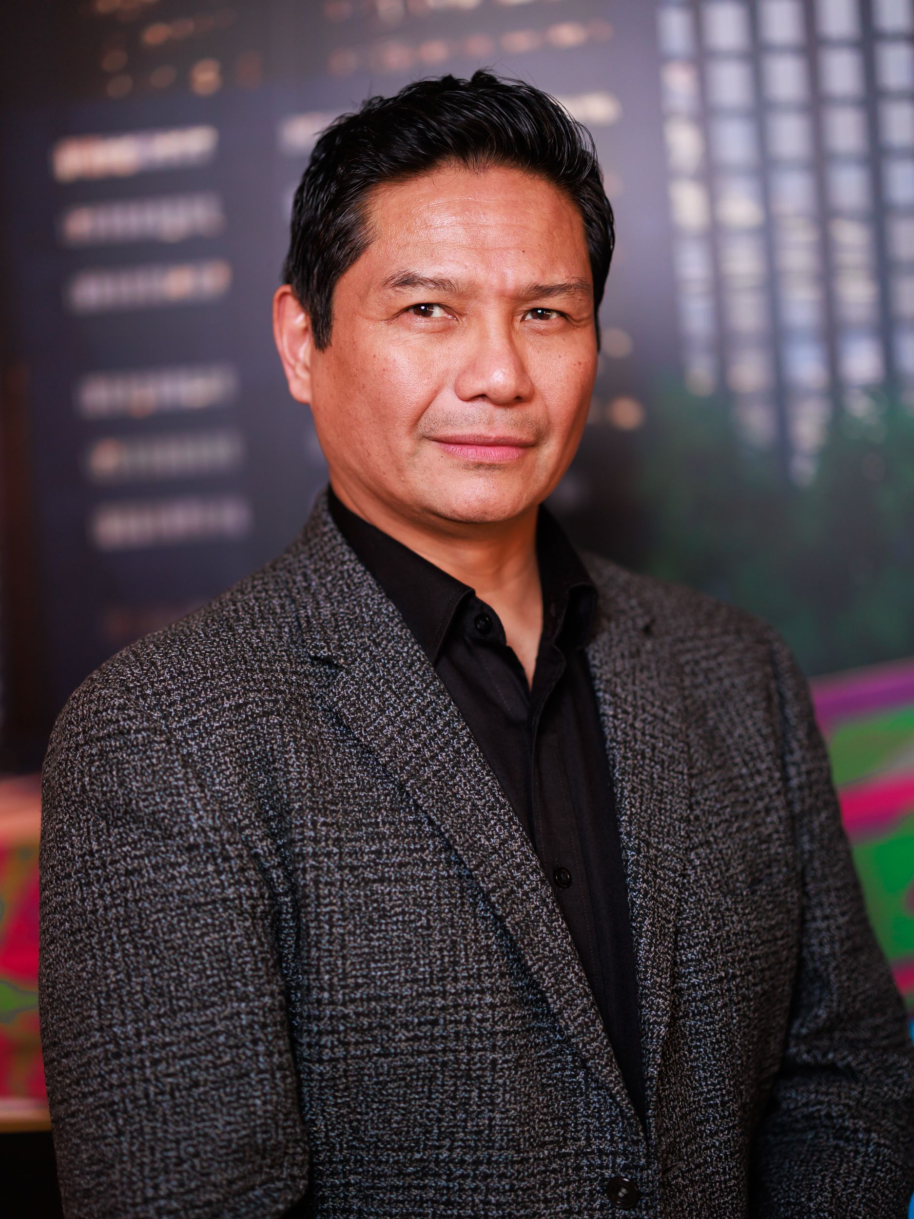 A man in a suit and black shirt is posing for a picture.