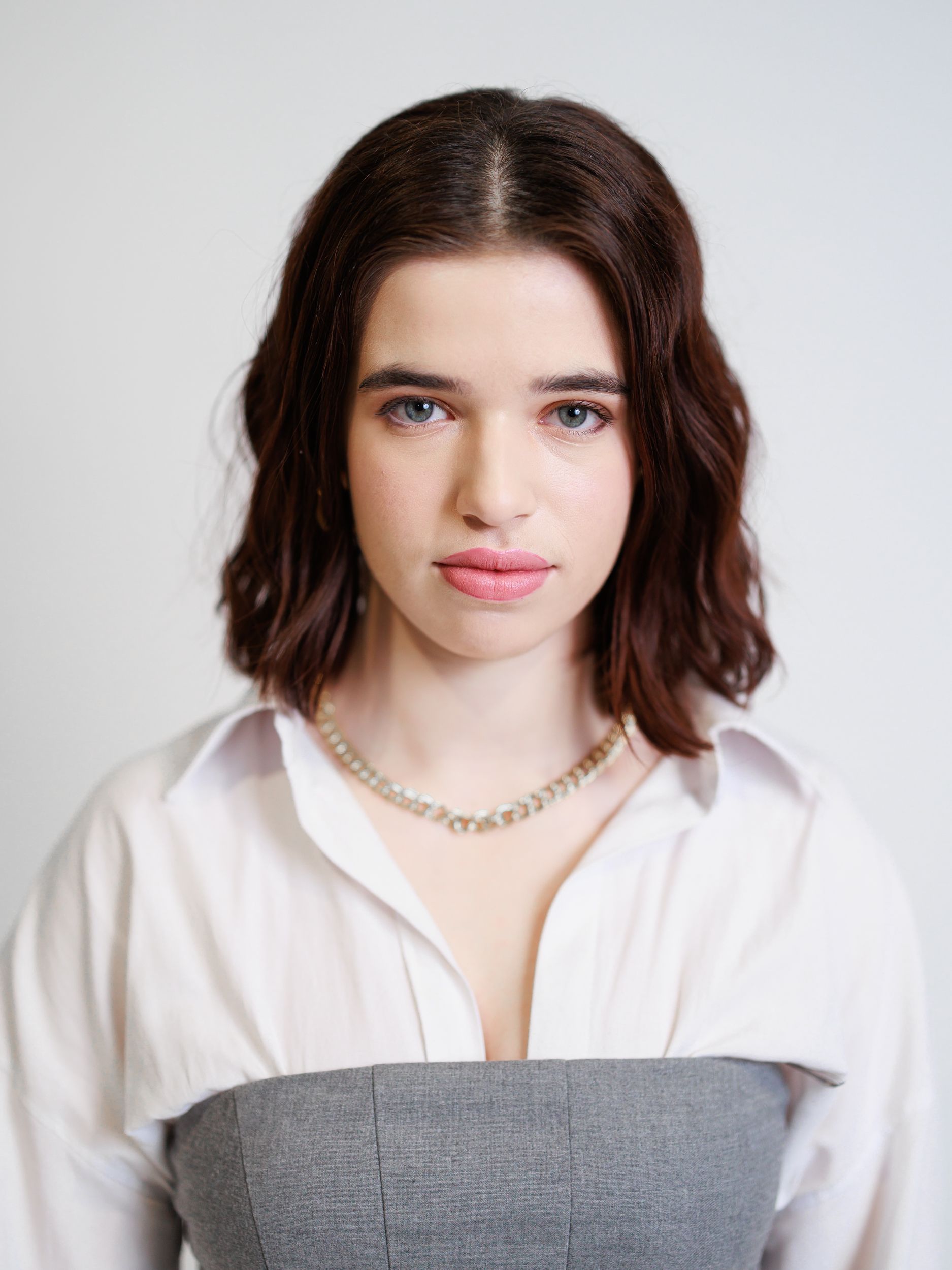 A woman wearing a white shirt and a necklace is looking at the camera. Toronto Headshot Photography